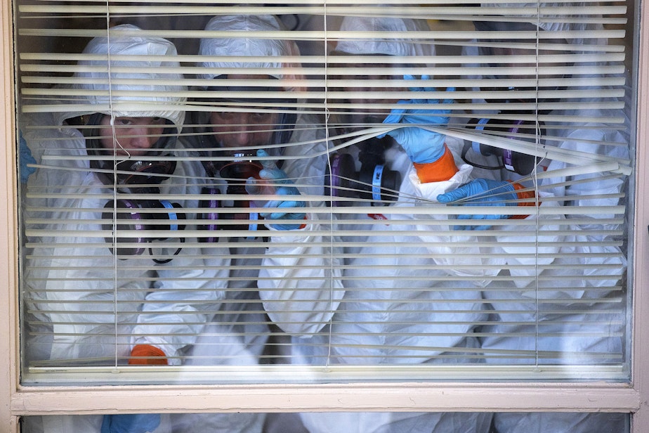 caption: Members of a ServPro cleaning crew look out of a window before taking a break from cleaning the interior of the Life Care Center of Kirkland, the long-term care facility at the epicenter of the coronavirus outbreak in Washington state, on Wednesday, March 11, 2020, in Kirkland.