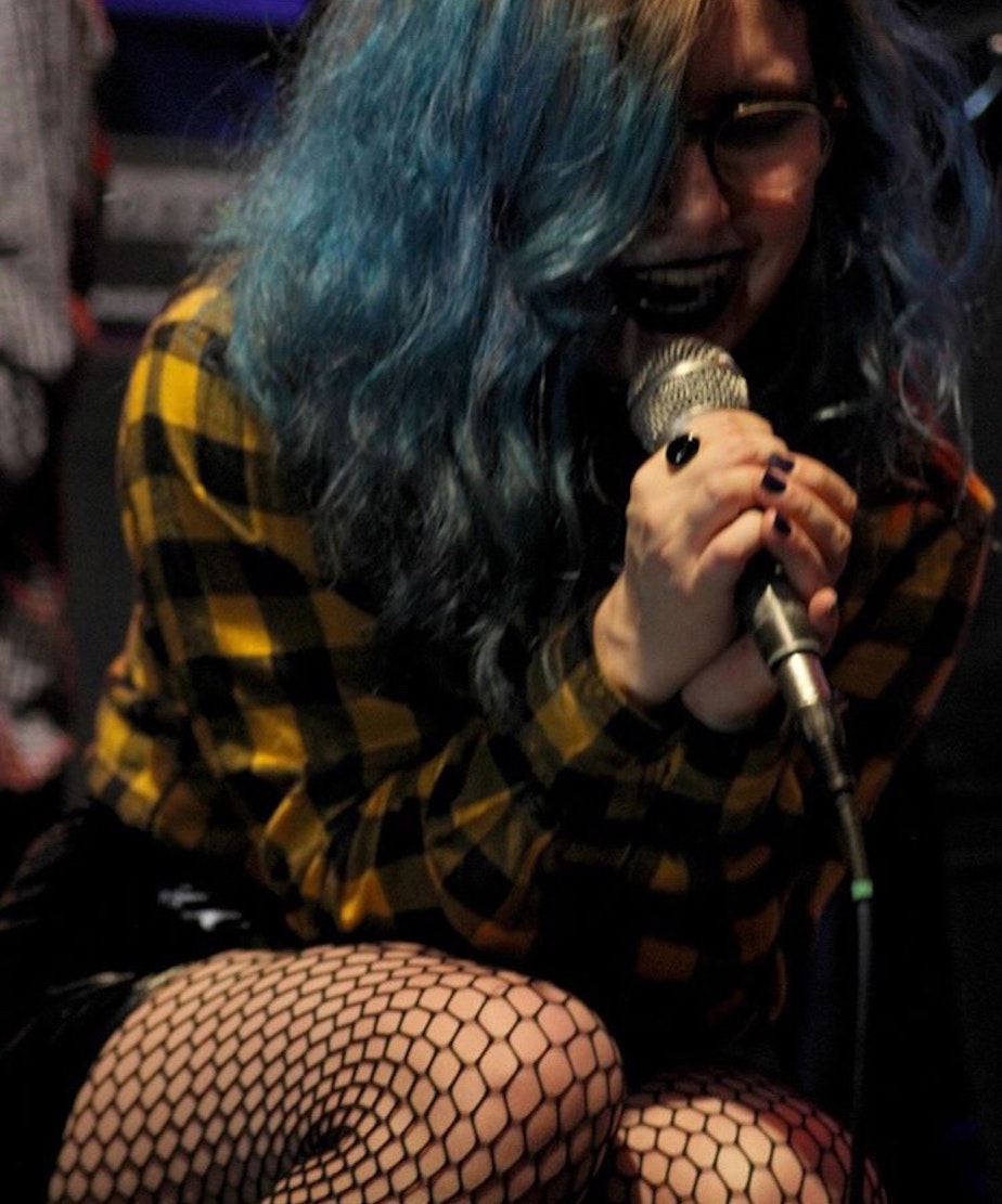 caption: Mimi H. sings into a microphone. She says transferring to Nova High School was her "saving grace."