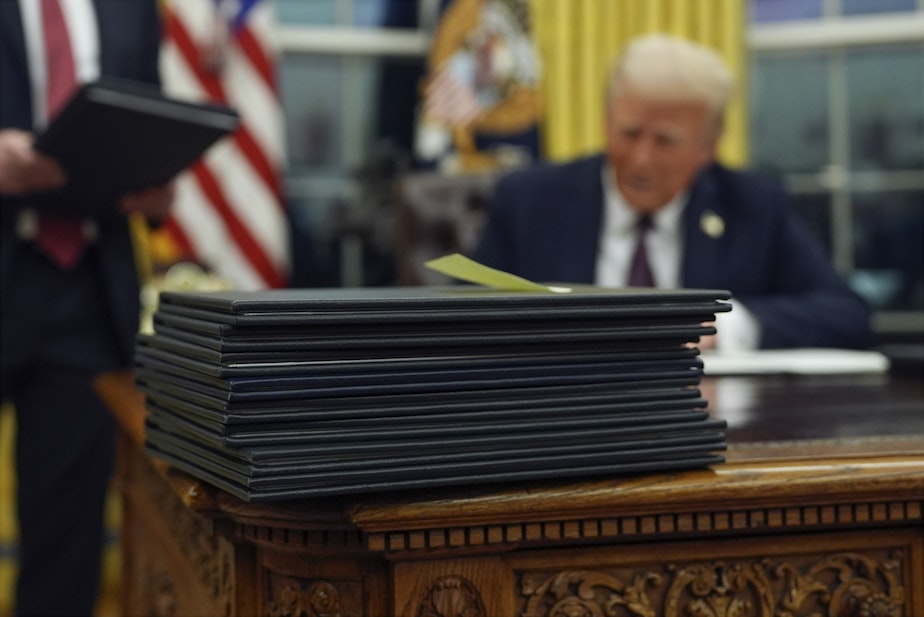 caption: FILE - President Donald Trump signs executive orders in the Oval Office of the White House, Jan. 20, 2025, in Washington.