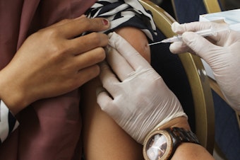 caption: A COVID booster is administered in Jakarta, Indonesia.
