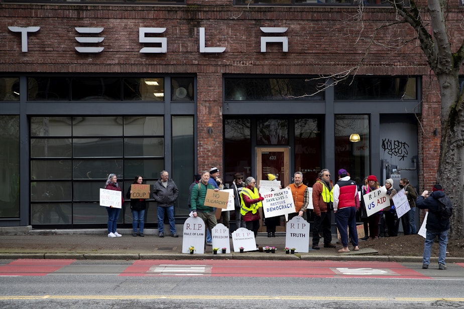 caption: The Troublemakers group protested in front of the Tesla showroom in South Lake Union on Thursday, Feb. 13, 2025, in Seattle.