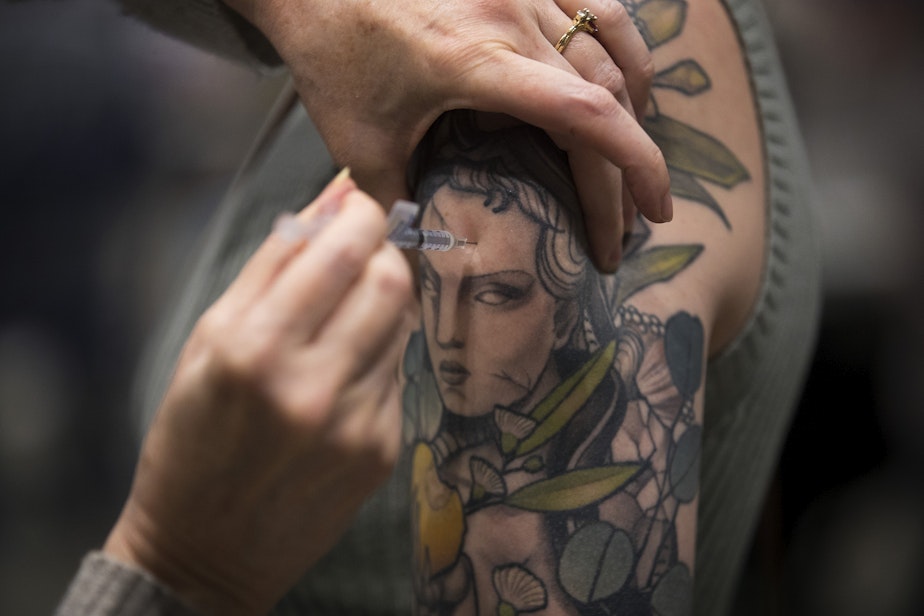 caption: Lauren Alexander is vaccinated against Covid-19 on Thursday, April 15, 2021, at Lumen Field Event Center in Seattle. As of Thursday, anyone 16 years of age and older is eligible.