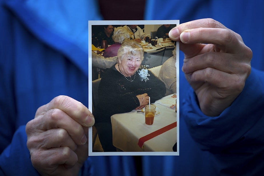 caption: Pat Herrick holds a picture of her 89-year-old mother, Elaine Herrick, at the Life Care Center of Kirkland on Thursday, March 5, 2020, in Kirkland. Elaine Herrick had died early Thursday morning while in the care of Life Care Center amid a deadly COVID-19 outbreak. Seven hours after learning of her mother's death, Pat Herrick received a call from Life Care: her mother was doing great. She had no fever and was showing no symptoms of COVID-19. Herrick alerted them of her mother's death.