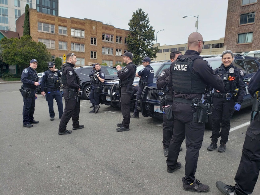 caption: A large group of police set up near the site of a Starbucks rally March 11 outside the University District Starbucks in Seattle. At least one officer is carrying a pepper ball gun.