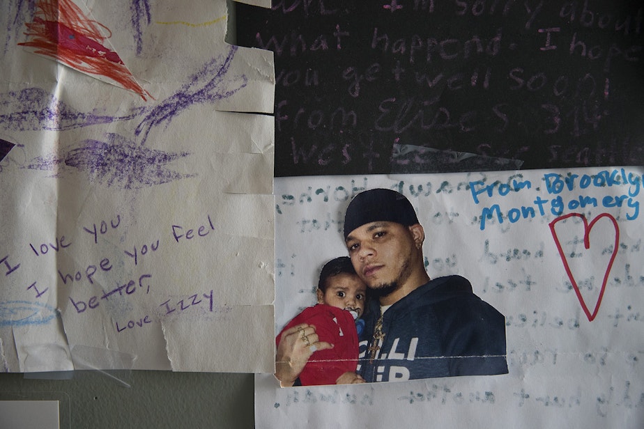 caption: A picture of DaShawn Horne holding his son Deion is taped to a poster on the wall of his hospital room on Friday, April 13, 2018, at Harborview Medical Center in Seattle.