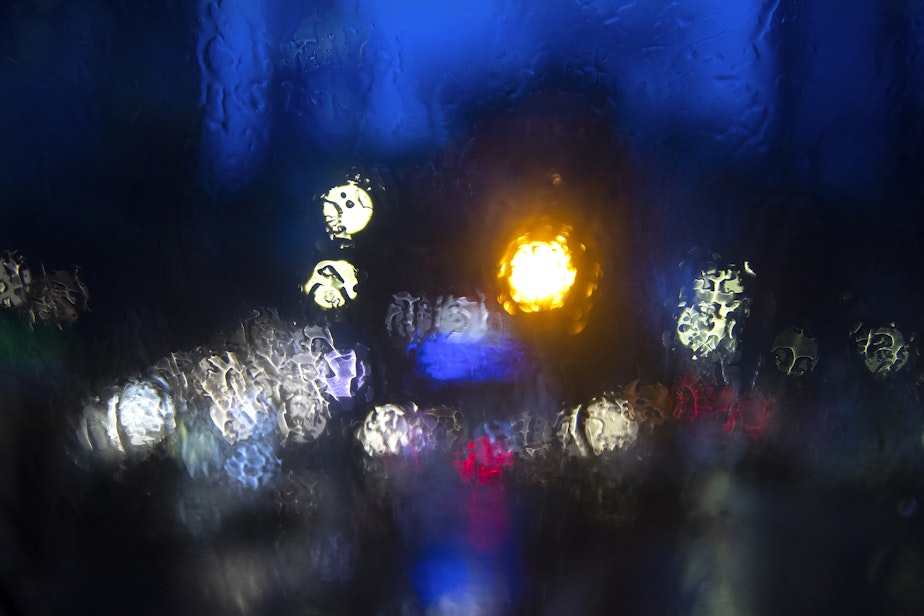 caption: Street lights are visible through a windshield obscured by rain on Tuesday, February 25, 2025, in downtown Seattle.