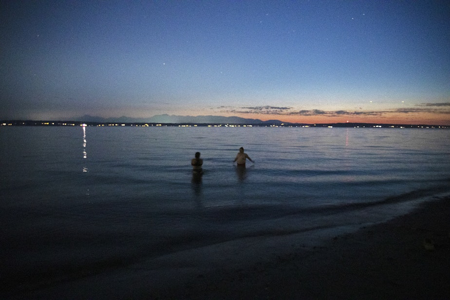 caption: Friends swim in Puget Sound at dusk on Friday, August 2, 2024, at Golden Gardens Park in Seattle.