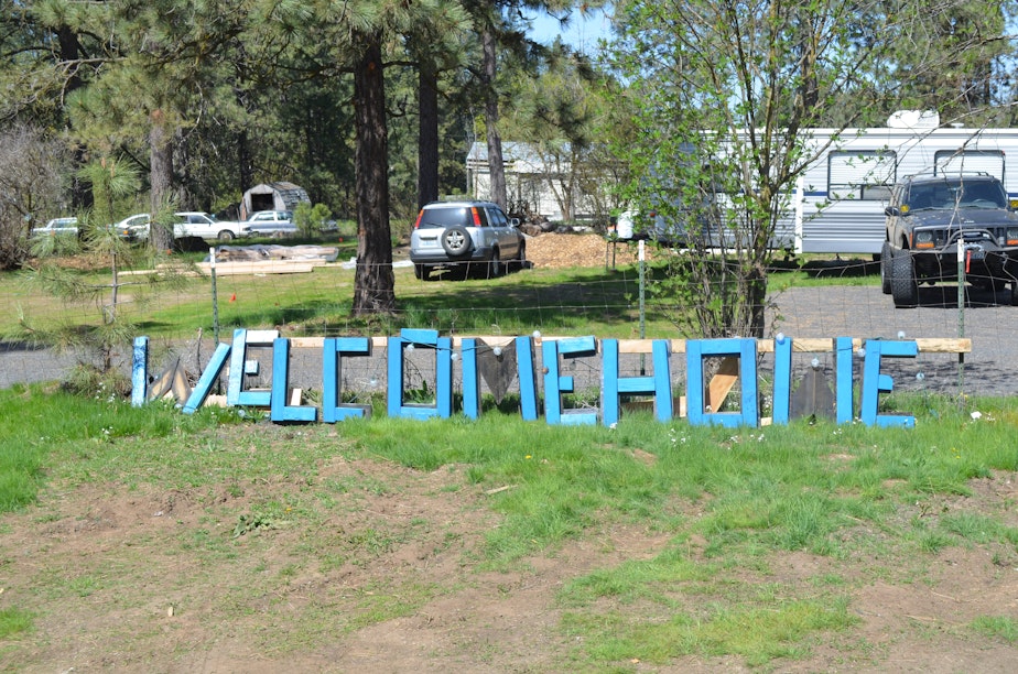 caption: A "Welcome Home" sign rests against the fence outside the home on the outskirts of Spokane where Sergey Kostenyuk and Mary Loisate live with their two sons.