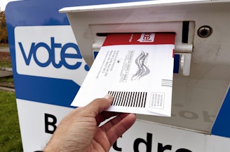 caption: A voter casts their ballot at a drop box in Seattle's Magnuson Park neighborhood on Thursday, Oct. 31, 2024.