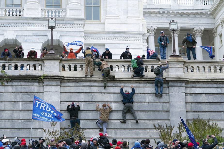 caption: In this Jan. 6, 2021 file photo rioting supporters of President Donald Trump climb the west wall of the the U.S. Capitol in Washington. Historians say Trump’s legacy and his electoral undoing will be largely shaped by rhetoric aimed at stirring his largely white base that tugged at the long-frayed strands of race relations in America.