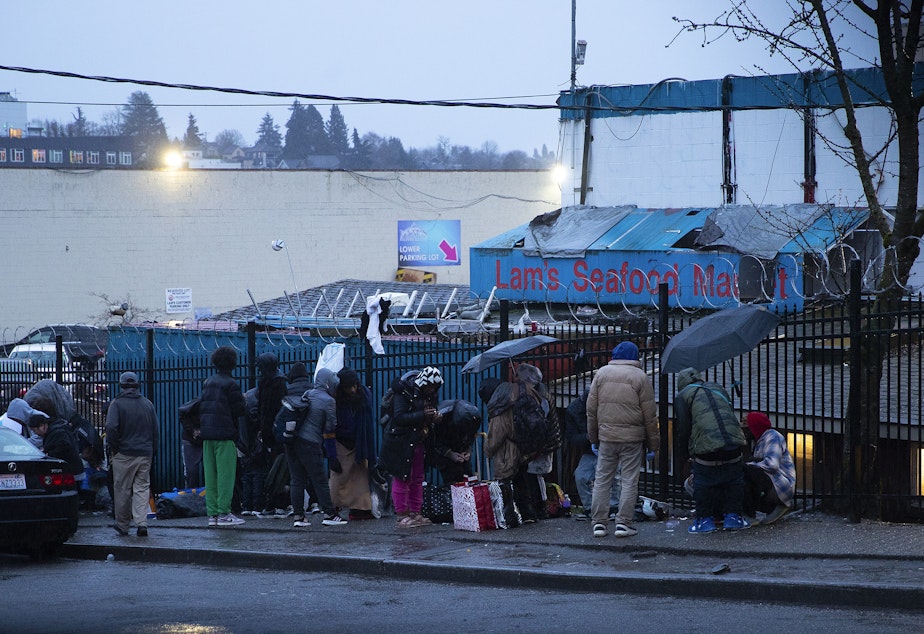 caption: A crowd of people is gathered on the sidewalk outside of Lam’s Seafood Market across from Hao Mai Park on Thursday, March 20, 2025, in Seattle’s Little Saigon neighborhood. 
