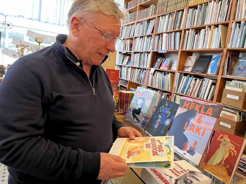 caption: Arundel Books founder Phil Bevis with this year's Seattle Indie Bookstore Day passport, also published in Pioneer Square across the street.