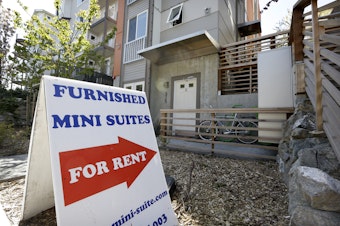 caption: In this photo taken Wednesday, April 24, 2013, a sign points toward a new building holding tiny apartments, in Seattle. 