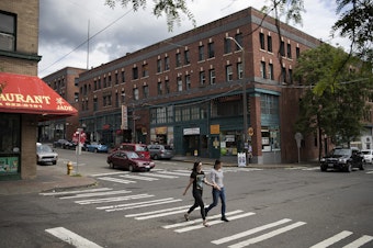 caption: Two women walk through the intersection of South King Street and 7th Avenue South, in the Chinatown-International District on Tuesday, June 13, 2017, in Seattle. 
