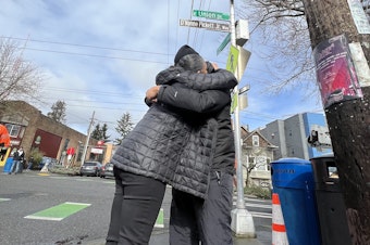 caption: Nicky Chappell shares a hug under the new street sign honoring her son, D'Vonne Pickett Jr., who was fatally shot last October near his business in Seattle's Central District.
