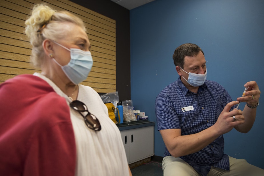 caption: Aaron Syring, owner and pharmacist at Island Drug, prepares to vaccinate Dawne'ne Jewett against Covid-19 on Wednesday, April 7, 2021, at Island Drug in Oak Harbor. Jewett drove from Langley to get the vaccine.