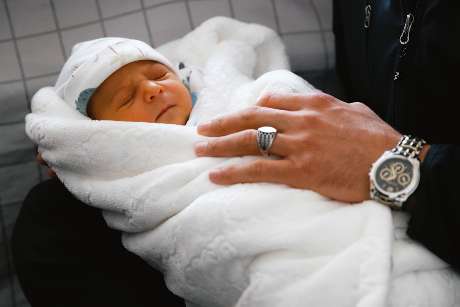 caption: Jabar Mahmoudi holds his one-week-old son, Omar, on Monday, March 31, 2025, at his brother-in-law’s apartment in Kent.